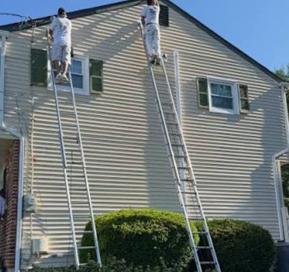 Two painters on ladders painting a two-story home exterior